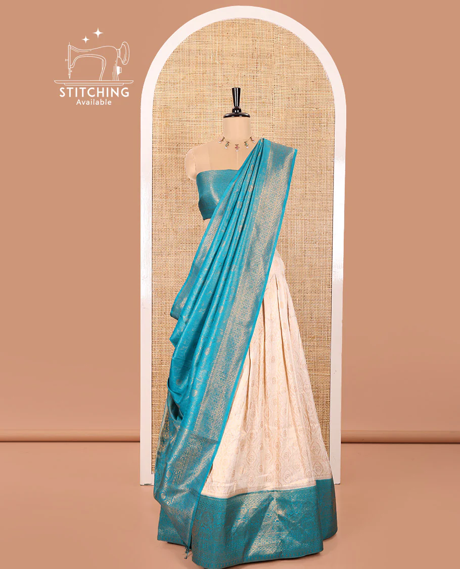 Cream and Blue Banaras Softy Half-Saree Featuring Jacquard Design All Over the Skirt, Decorated with a Contrast Geometric Zari Design Border, Paired with a Jacquard Blouse, and a Banaras Softy Dhavani with Floral Jaal Jacquard Design