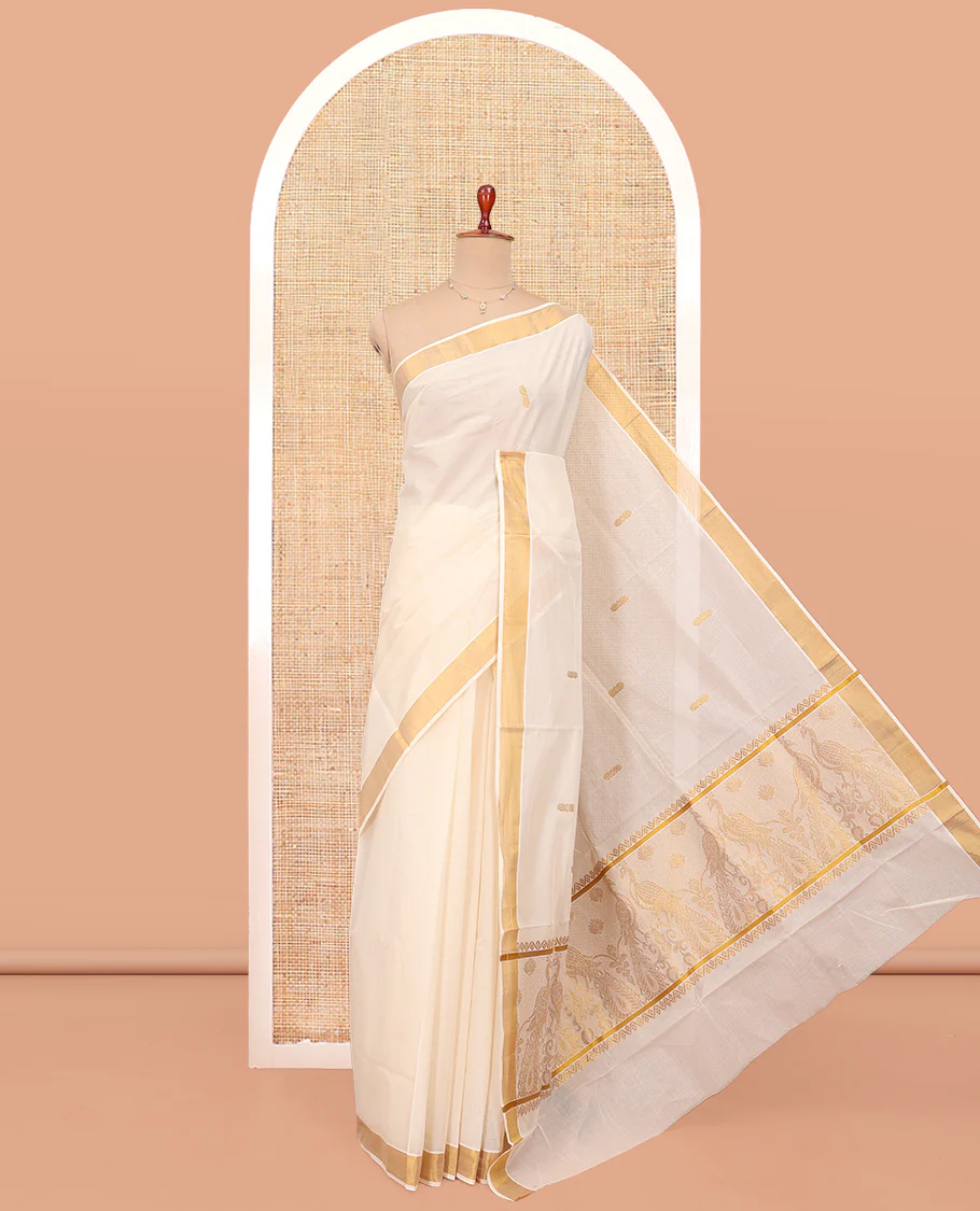 Cream Kerala Cotton Saree, Graced with Zari Buttas All Over Its Body, a Zari Bavanji Border, Pallu Woven with Peacock Designs, and Paired with a Matching Blouse