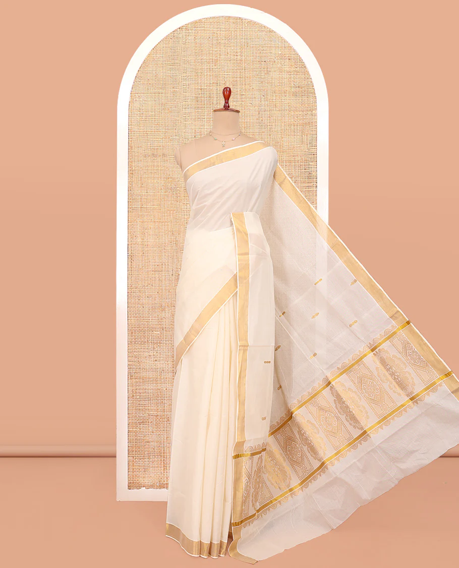 Cream Kerala Cotton Saree, Ornamented with Zari Buttas All Over Its Body, a Zari Bavanji Border, Pallu of Intricate Designs, and Paired with a Matching Blouse