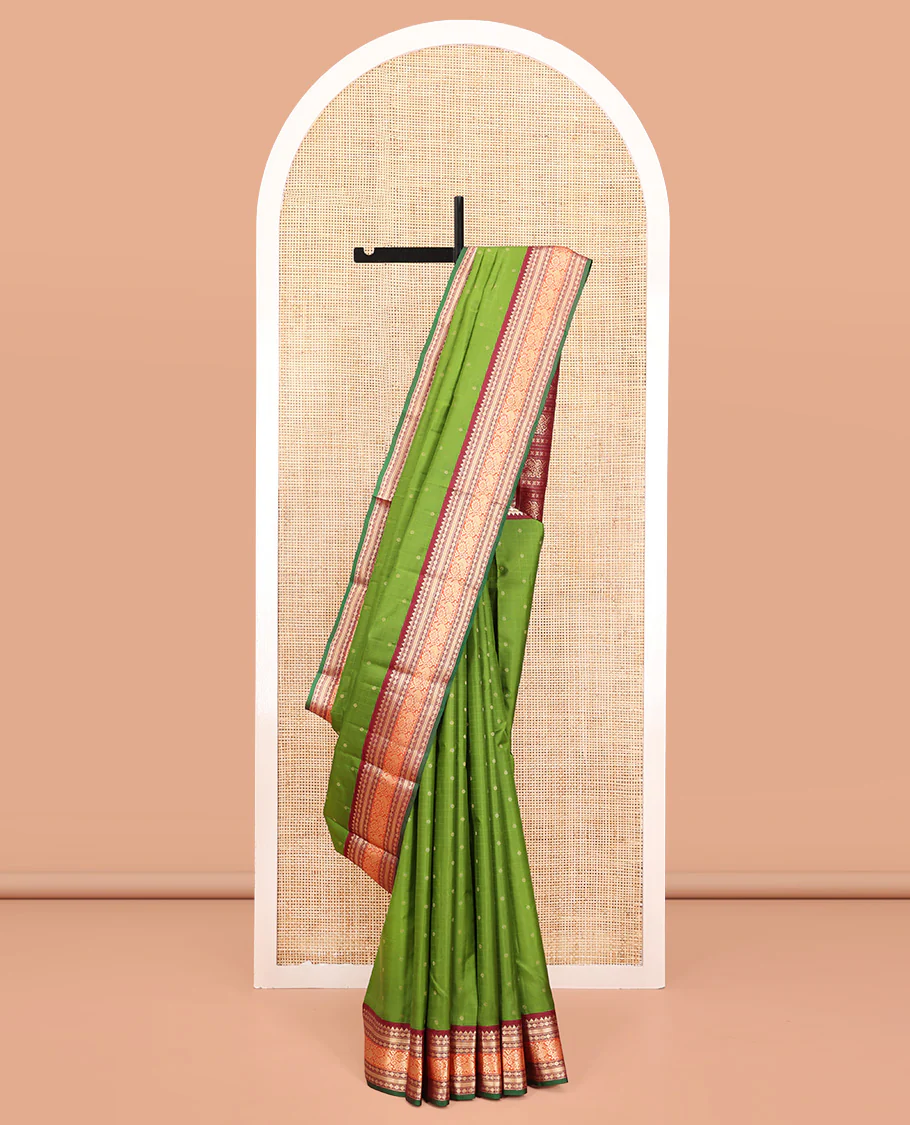 Green Vasundhara Silk Saree, Sparsely Woven with Zari Buttas All Over Its Body, Complemented by a Contrast Border of Rekku, Poun, Kathir, and Mayil Designs, Pallu Steeped with the Same Border Designs, and Paired with a Contrast Blouse