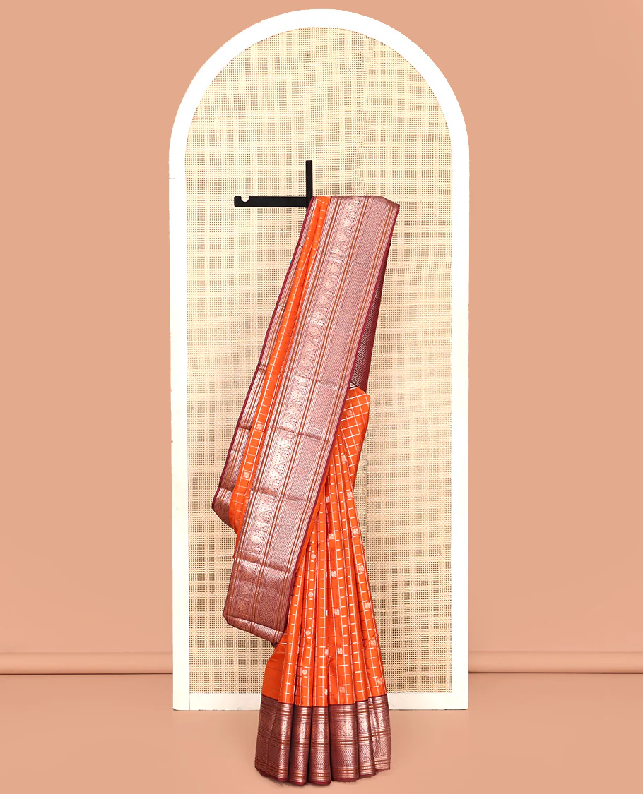 Orange Vasundhara Silk Saree, Meticulously Crafted with Zari Butta Enclosed Checks, Complemented by Contrast Border of Thilakam Mokku, Rettai Neli, Iruthalai Pakshi, and Ara Maadam Designs, Grand Jaal Pallu and Paired with a Contrast Blouse