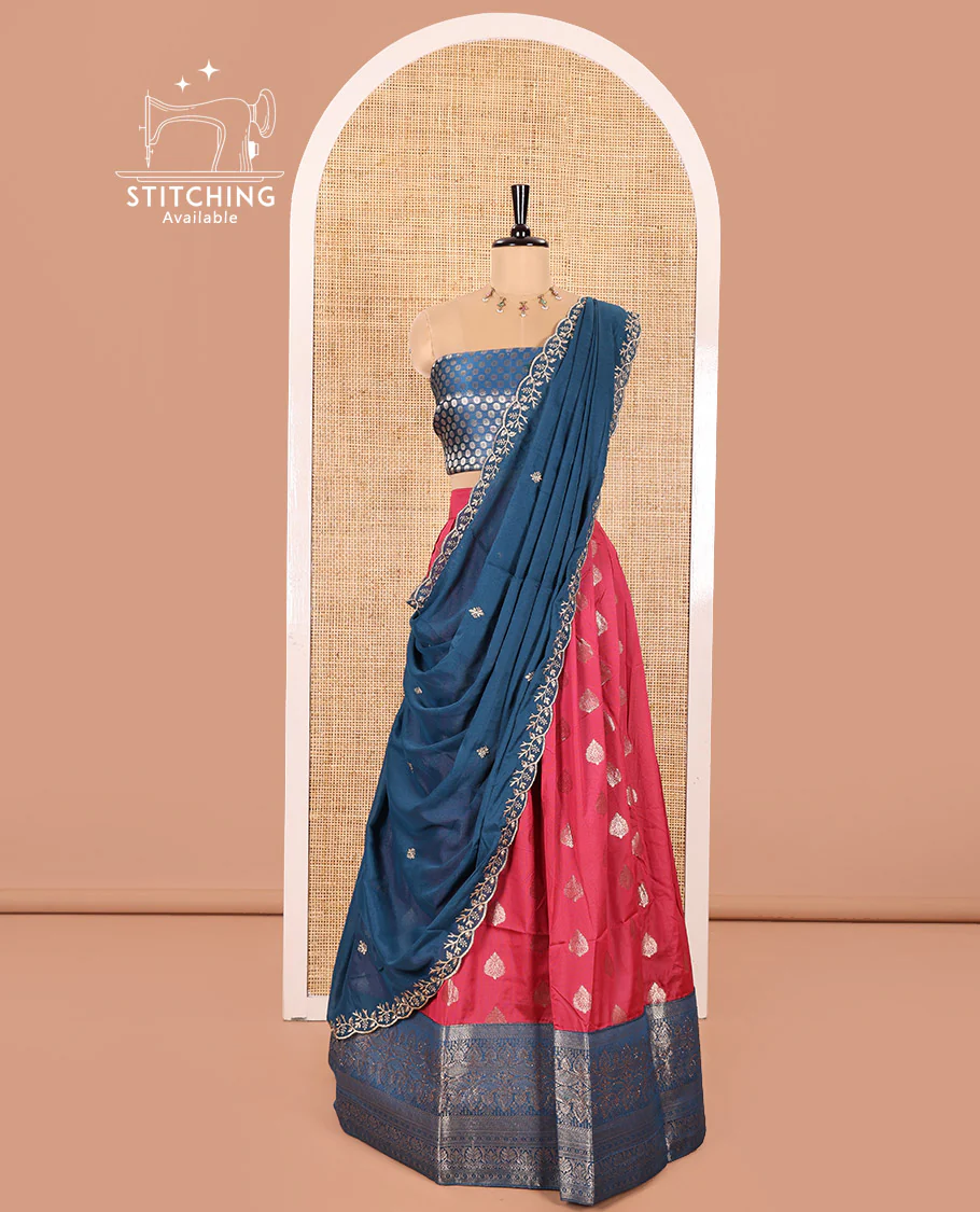 Peacock Blue and Rani Pink Semi-Banaras Silk Half-Saree Featuring Zari Buttas All Over the Skirt, Highlighted with a Contrast Traditional Zari Design Border, Rudraksham Motifs Woven Blouse, and a Shimmer Georgette Scallop-Embroidered Dhavani