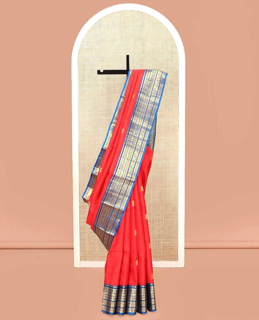Red Vasundhara Silk Saree, Subtly Sparkled With Zari Buttas All Over Its Body, Complemented by Contrast Border of Salngai, Muthu, Kamalam, Jada Nagam, and Mayil Designs, Grand Pallu and Paired with a Contrast Blouse