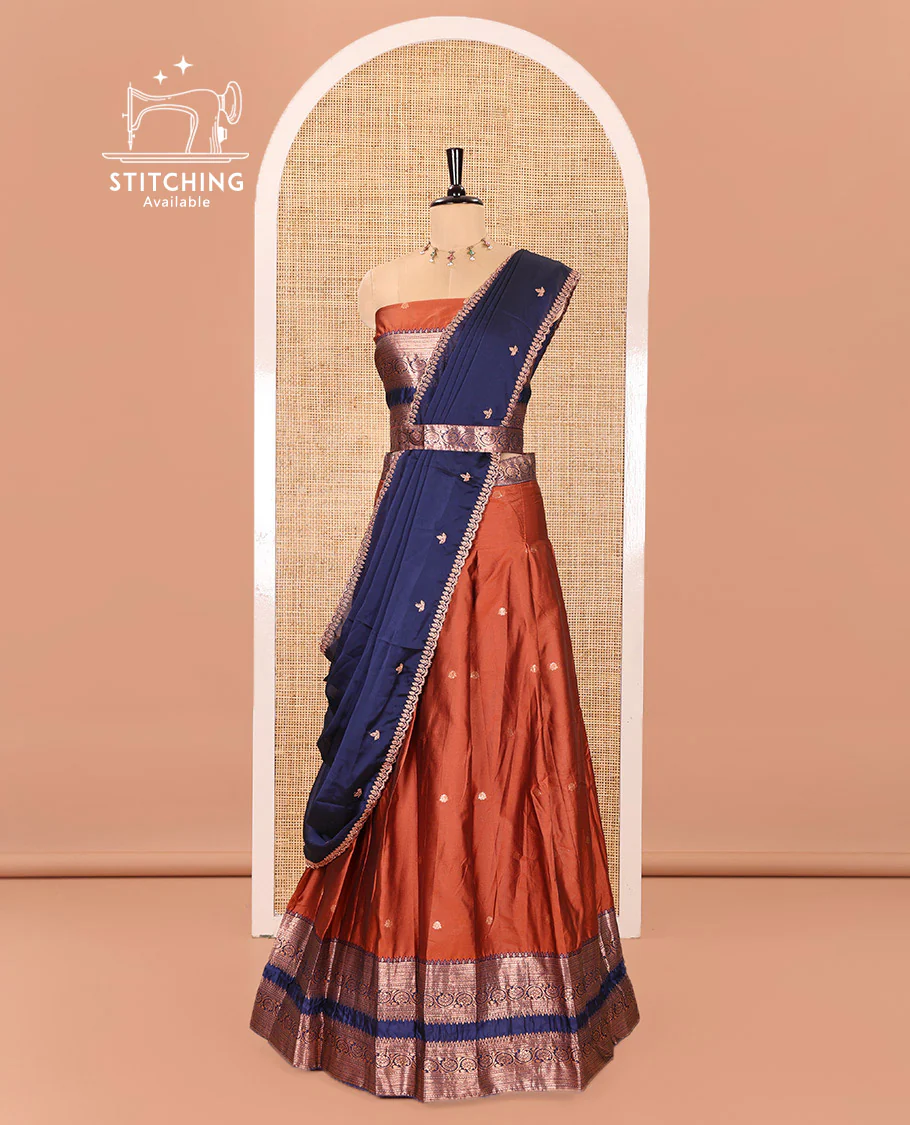 Rust and Blue Semi-Banarasi Half-Saree Featuring Zari Buttas Skirt, Complemented by Contrast Rettai Pettu, Traditional Border of Floral Creeper Designs, Paired with a Matching Blouse, and a Satin Georgette Embroidered Scallop Dhavani