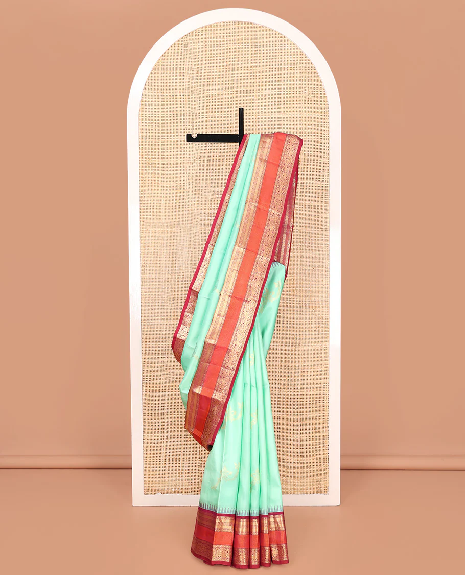 Turquoise Vasundhara Silk Saree, Meticulously Crafted with Zari Buttas on Its Body, Complemented by Contrast Border of Muthu, Mayil Kann, Chakram, Mayil, and Kuthirai Designs, an Intricately Designed Pallu, and Paired with a Contrast Blouse